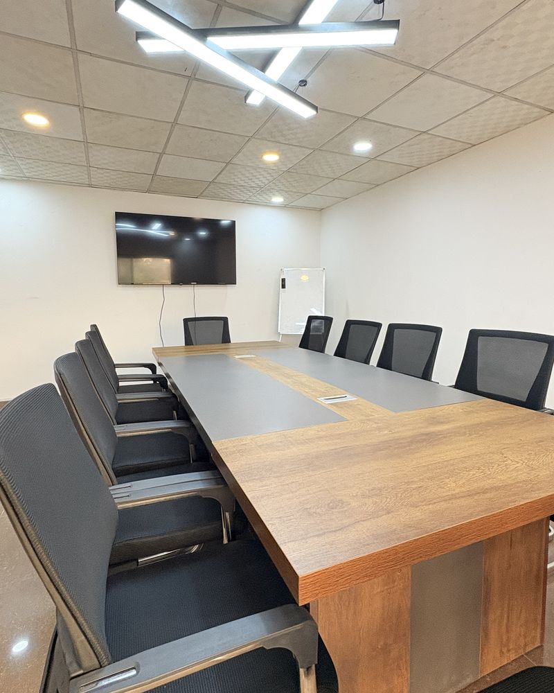 Salle de formation avec grande table en bois, écran mural et luminaire design